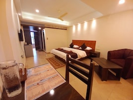 Una camera d'albergo con un letto, una scrivania, una sedia, un televisore e un frigorifero.