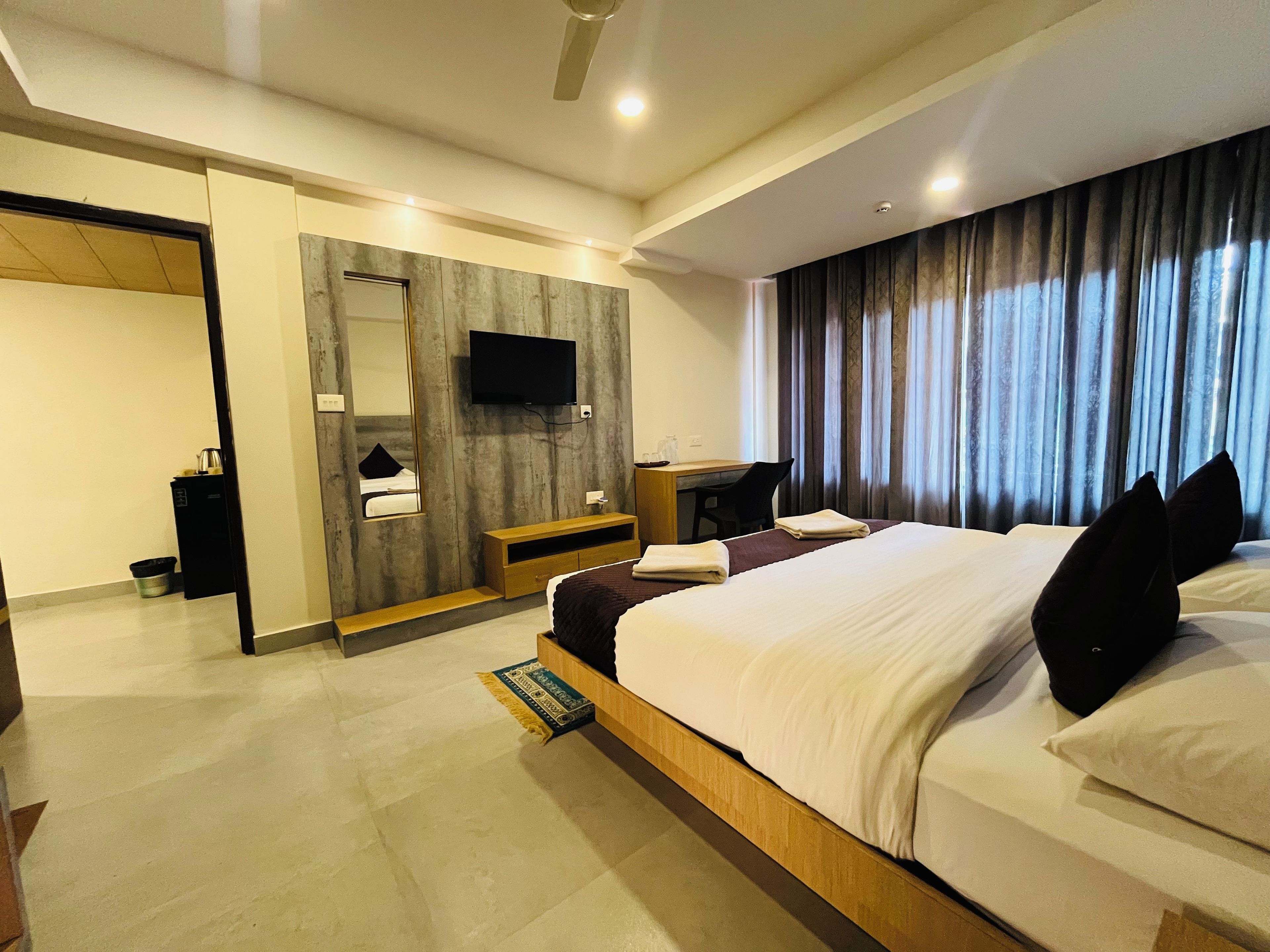 Una habitación de hotel con una cama, un escritorio, un televisor y un baño.