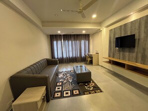 A modern living room with a sofa, a coffee table, a TV, and a ceiling fan. - Famafa Beach Resort (Arambol)