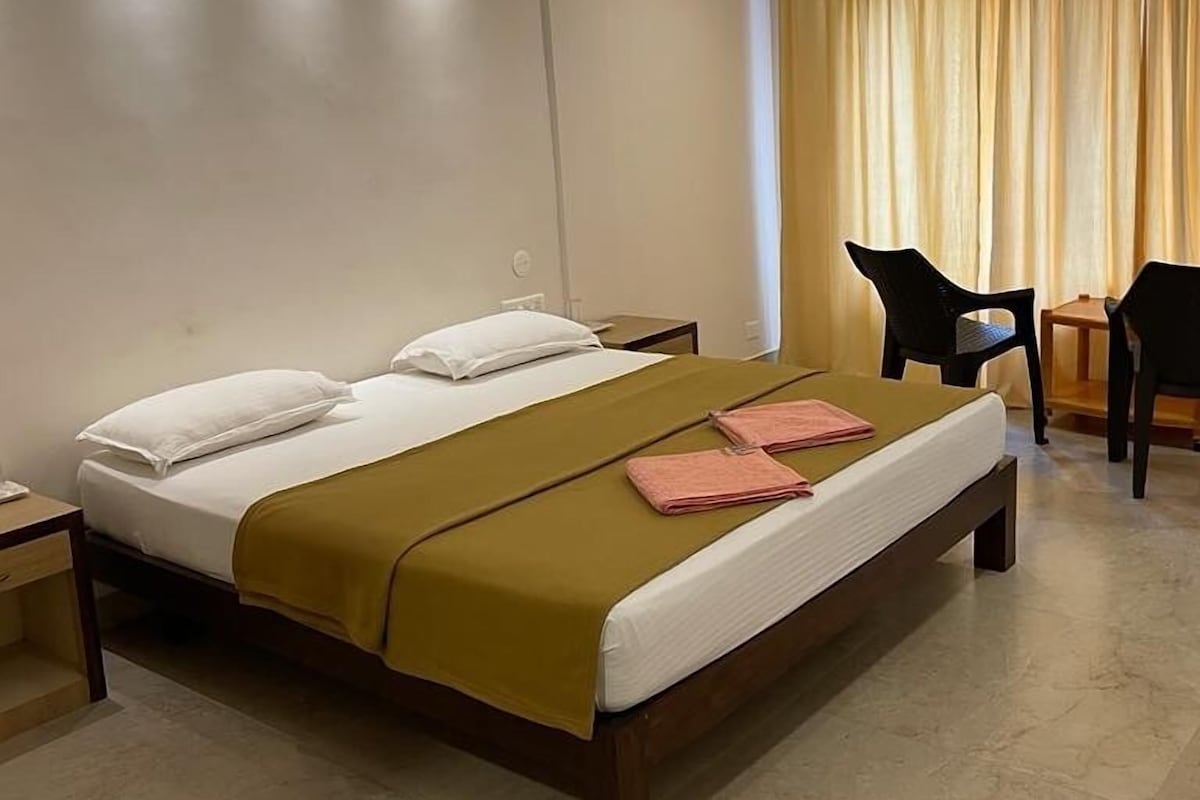 A hotel room with a bed, a desk, a chair, and a curtain.