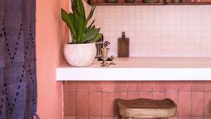 Una cocina con encimera blanca, una planta en maceta y un taburete de madera.