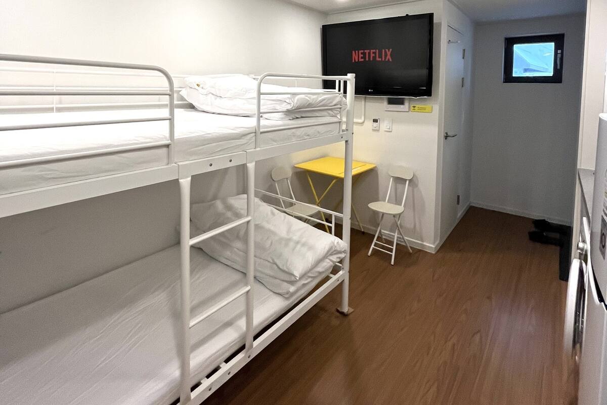 A bunk room with a desk, chair, and a television displaying "NETFLIX".