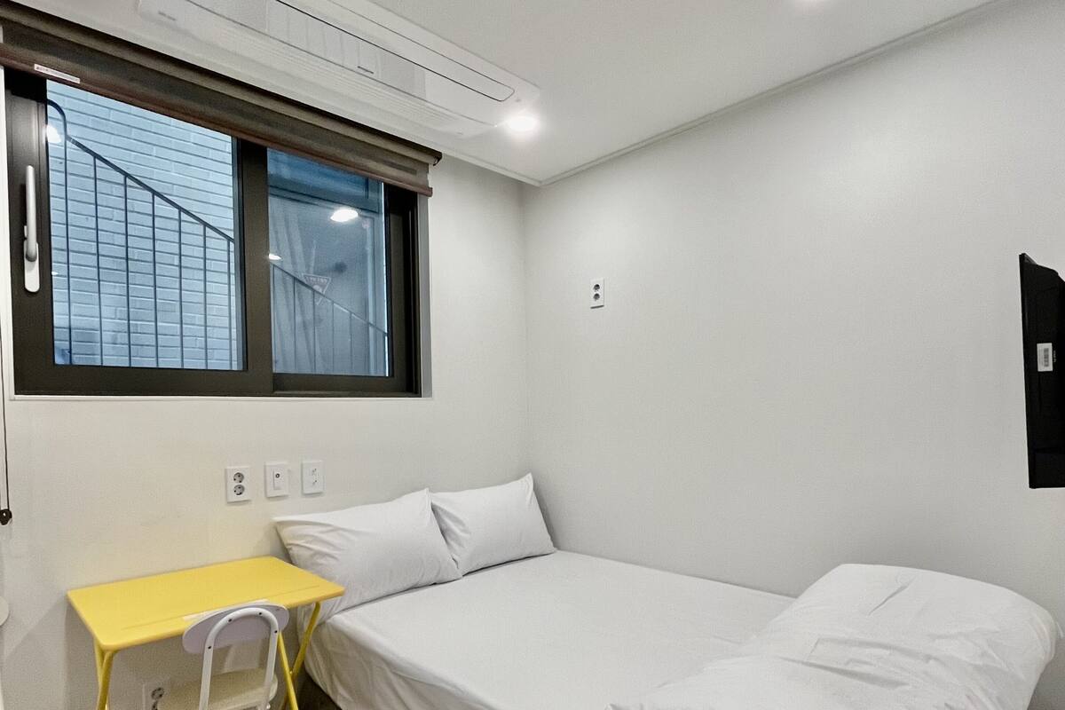 A small, clean room with a bed, a desk, and a chair.