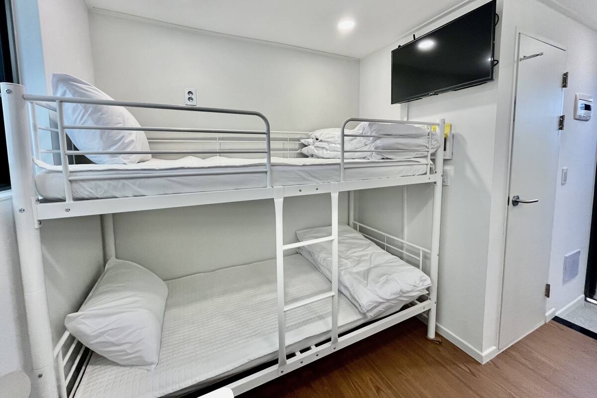 A bunk bed room with a television mounted above the upper bunk.