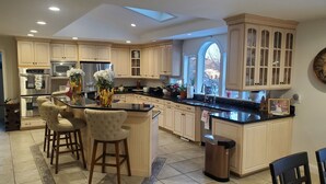 A spacious kitchen with a large island, built-in appliances, and a view through a window. - Hilltop Mansion Near Saratoga @ Rebecca's Fountain with Chef, Masseur & Fun (Niskayuna)