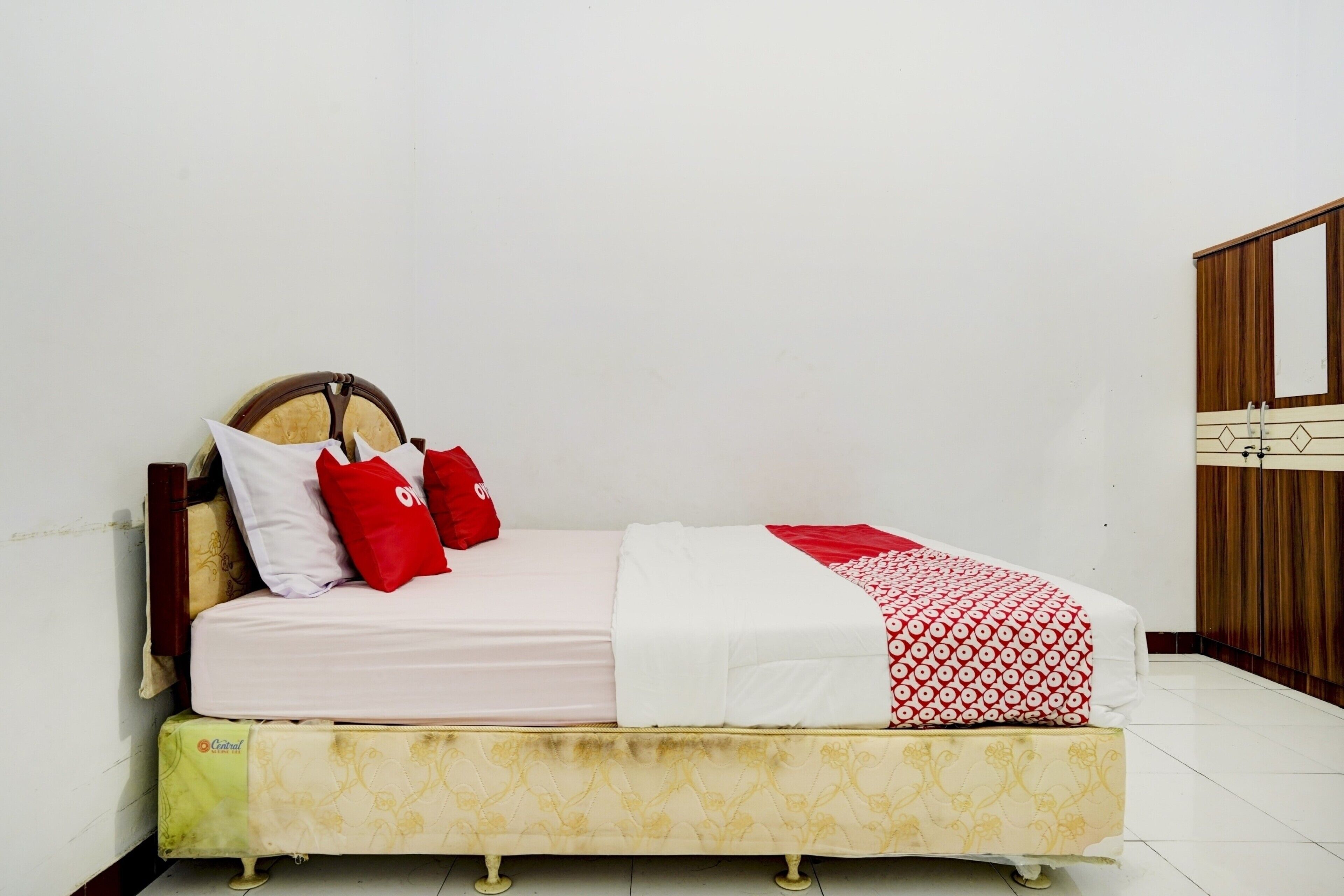 A bed with a wooden headboard, two red pillows, and a patterned blanket.