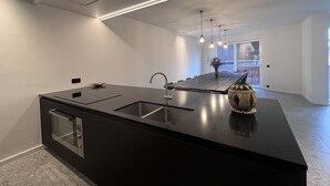 Una cocina moderna con una isla grande, electrodomésticos de acero inoxidable e iluminación colgante.