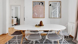 Een eetruimte met een ronde tafel, vier stoelen en twee abstracte schilderijen aan de muur.