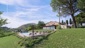 A stone house with a swimming pool and lounge chairs. - Podere Il Chiesino 8 2 (Montecatini Val di Cecina)