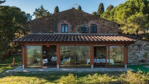 A stone house with a tiled roof and a glass-enclosed patio area. - Podere Il Chiesino 8 2 (Montecatini Val di Cecina)