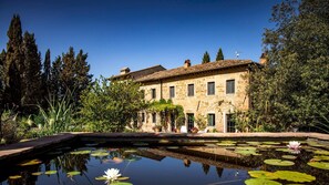 A stone building with a courtyard and a pond with water lilies.
