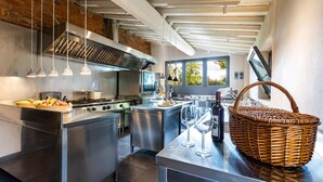 Een moderne keuken met roestvrijstalen apparatuur, een groot eiland en uitzicht op het omliggende landschap door de ramen.