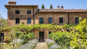 A stone building with multiple windows and a covered walkway with plants.