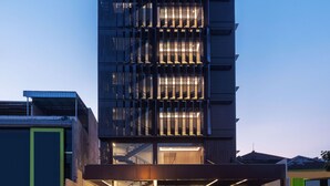 Un hotel moderno con una estructura de varios pisos, grandes ventanales y una entrada bien iluminada.