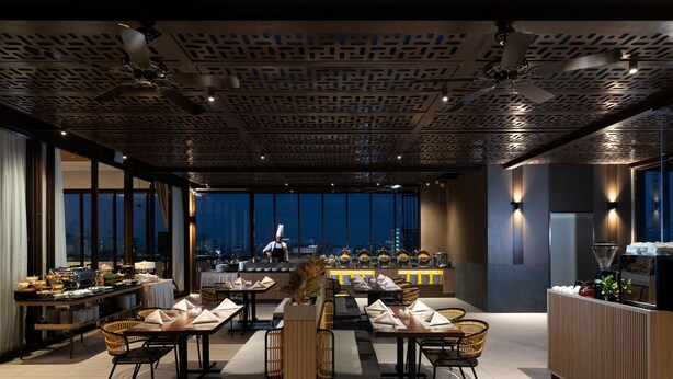 Un restaurante moderno con un chef preparando comida, una barra libre y vistas de la ciudad de noche.