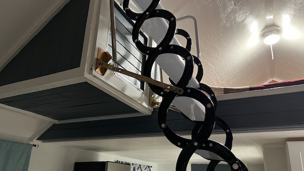 Ein Deckenventilator mit kreisförmigem Design, ein Fenster mit Jalousien und eine Tür mit Kleiderhaken.