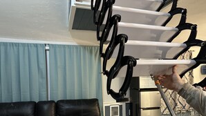 Ein Wohnzimmer mit einem schwarzen Ledersofa, einem Edelstahlkühlschrank und einer deckenmontierten Klimaanlage.