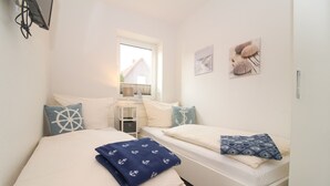 Quarto com duas camas, uma janela e decoração náutica.