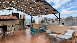 A rooftop terrace with outdoor seating, a pergola, and a view of the city skyline. - CDP 106 · Cute 1 bedroom in the Malecon (Puerto Peñasco)