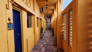 A narrow hallway with yellow walls, a blue door, and tiled flooring.