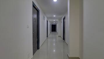 A long, narrow hallway with white walls and doors on both sides.