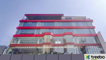 A multi-story building with a modern architectural design, featuring large glass windows and red accents.
