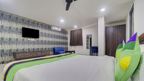 A hotel room with a large bed, a flat-screen TV mounted on the wall, a desk with a chair, and a wardrobe. - Treebo Destination Inn (Hyderabad)