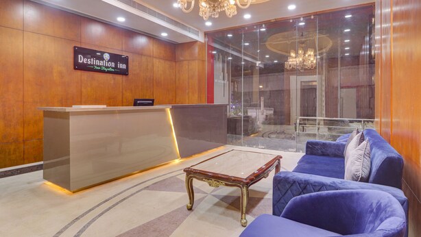 A reception area with a reception desk, a blue sofa, and a chandelier. - Treebo Destination Inn (Hyderabad)