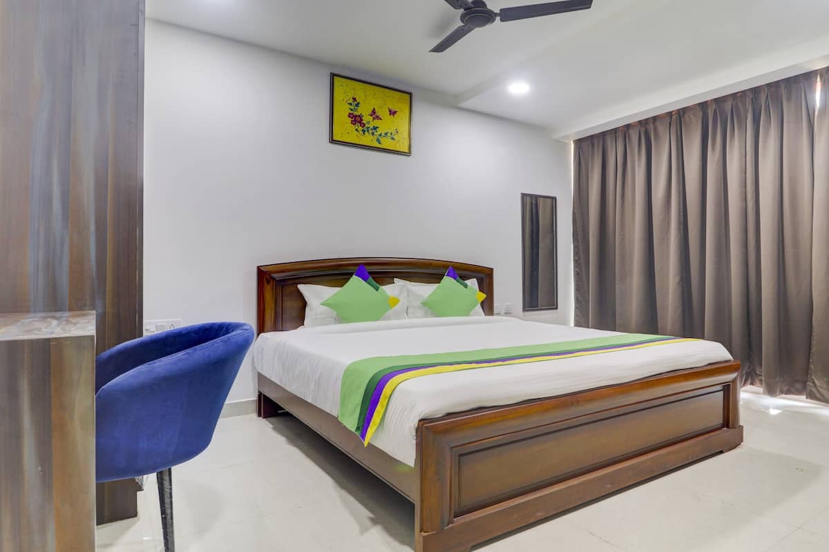 A bedroom with a wooden bed, a blue chair, a ceiling fan, and a window with curtains.