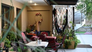 An outdoor patio area with tables and chairs, surrounded by potted plants and a decorative wreath. - Ducato di Aria  (Nafplio)