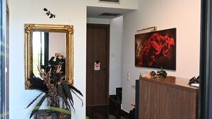 A hallway with a marble floor, a wooden reception desk, a framed mirror, and a red abstract painting on the wall. - Ducato di Aria  (Nafplio)