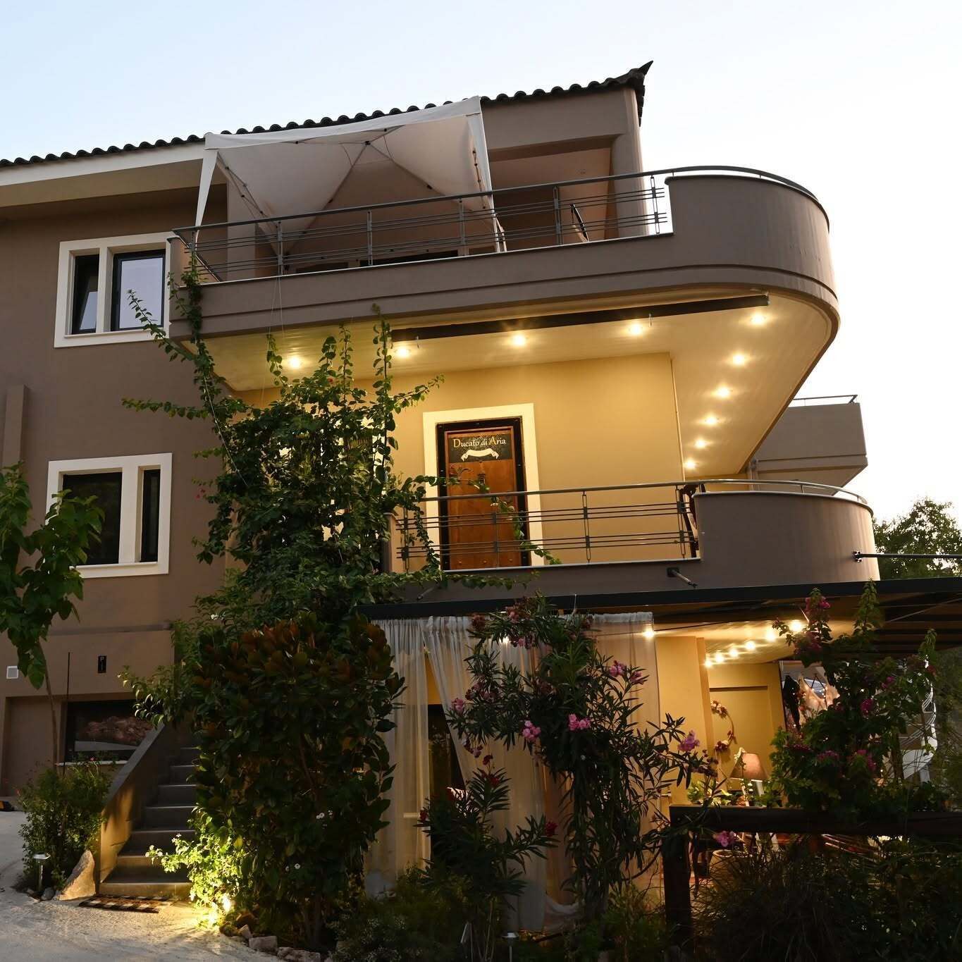 A two-story building with a balcony, a staircase, and a door with a sign.