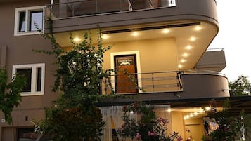 A two-story building with a balcony, a staircase, and a door with a sign.