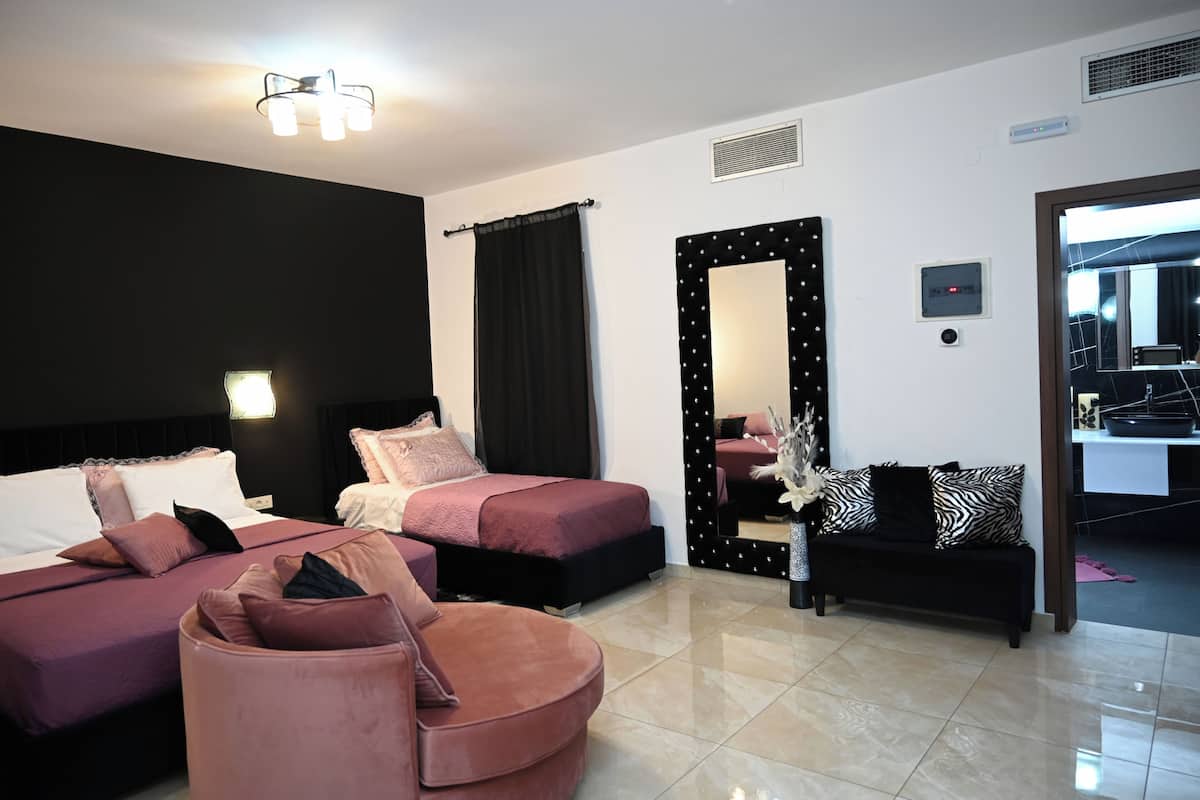 A modern hotel room with two beds, a sofa, and a mirror.