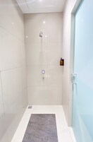 Un moderno espacio de ducha con puerta de vidrio, ducha y panel de control.