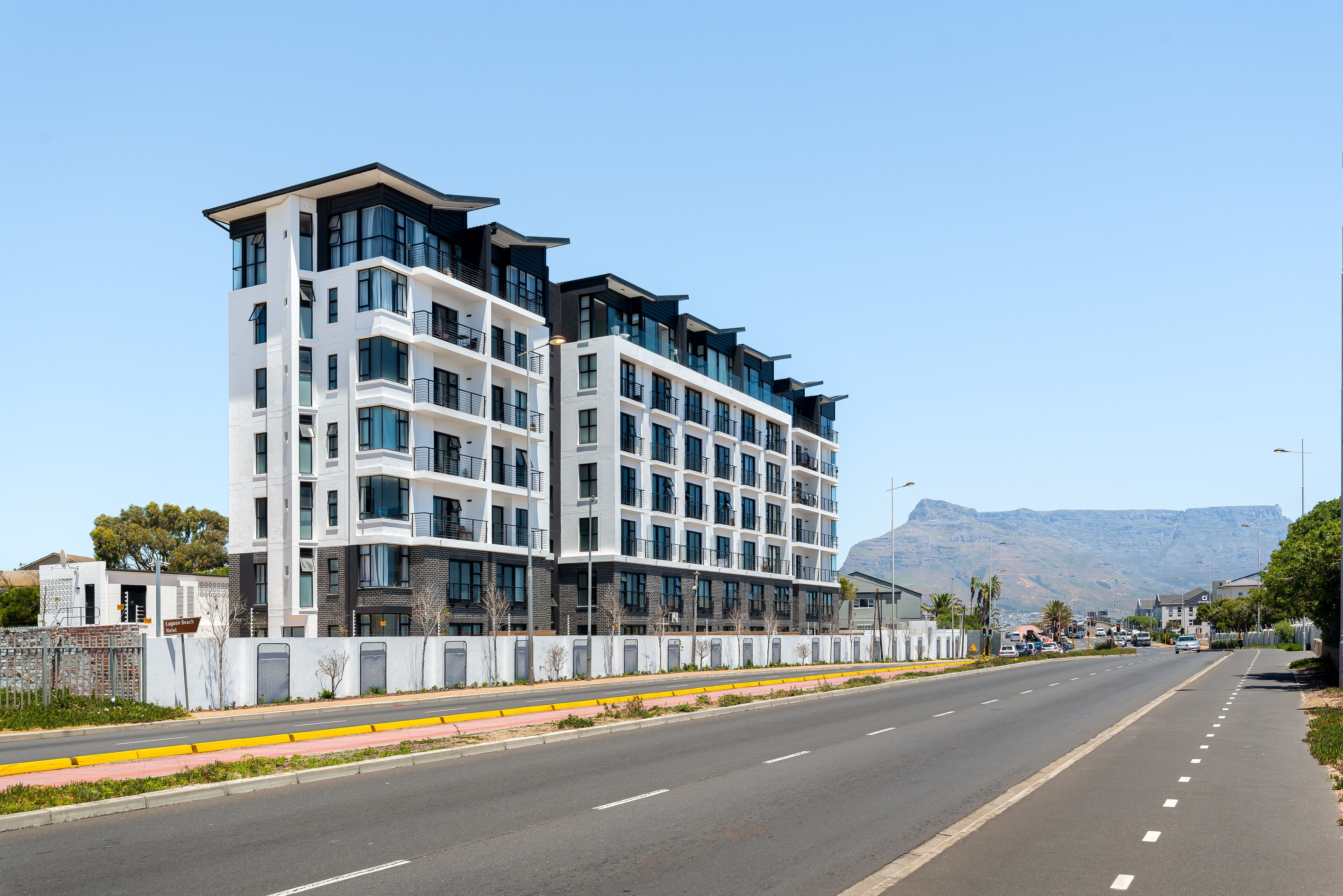 A modern multi-story hotel with a prominent entrance, large windows, and a view of the mountains in the background.