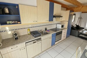 A kitchen with light wooden cabinets, a microwave, a dishwasher, and a sink. - Charming duplex with a shared pool (Cournillens)