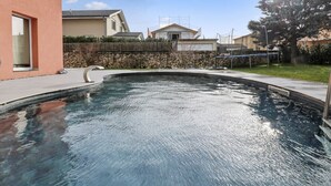 A swimming pool with a stone wall and a wooden fence in the background. - Charming duplex with a shared pool (Cournillens)
