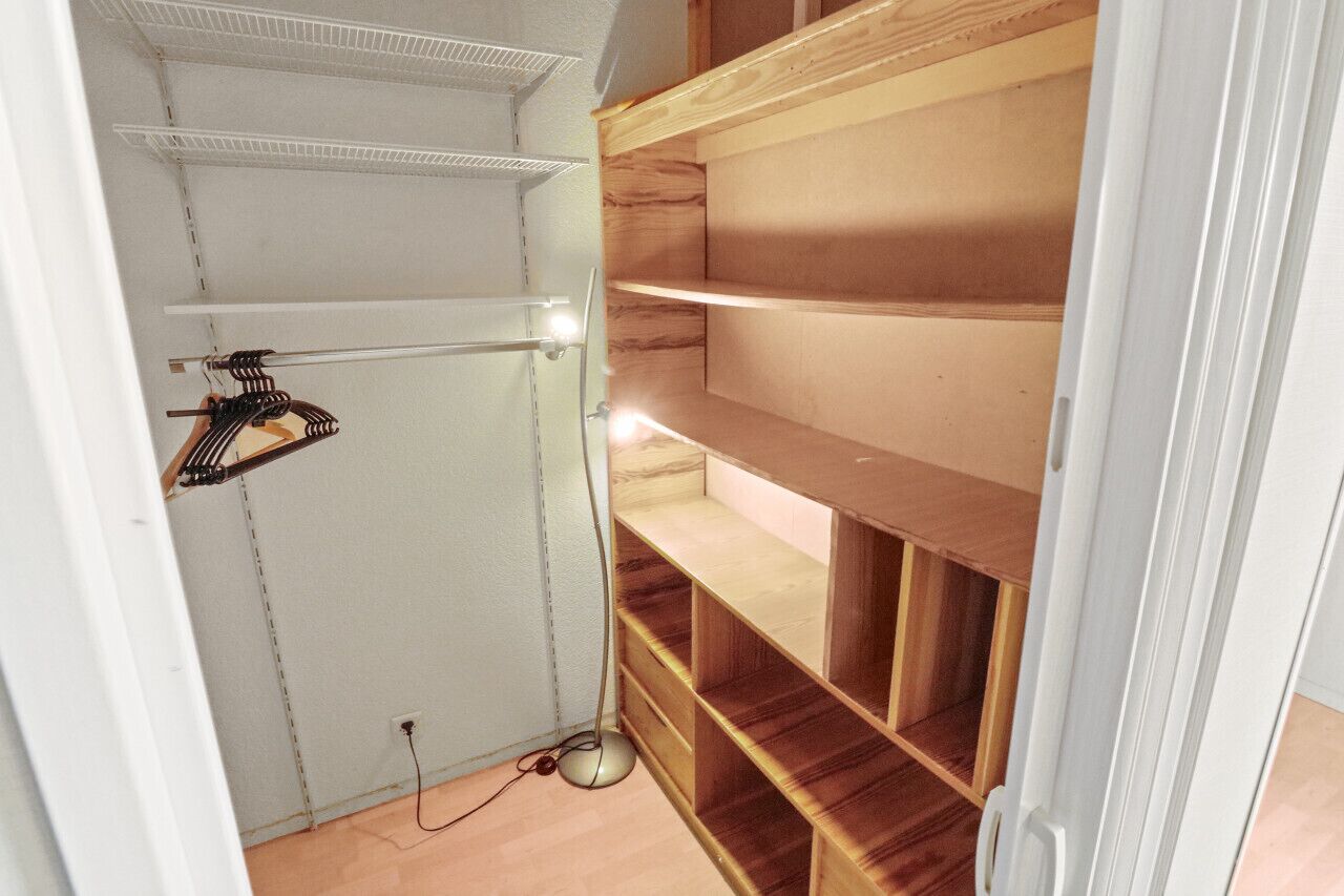 A walk-in closet with open shelving and a hanging rod.