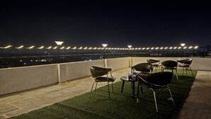 A rooftop terrace with outdoor seating and string lights.