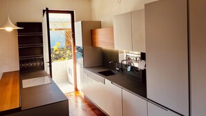 Une cuisine moderne équipée d’un four encastré, d’un évier et d’une fenêtre donnant sur un jardin.