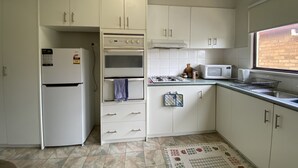 Keittiössä on valkoiset kaapit, sisäänrakennettu uuni, mikroaaltouuni ja kaasuliesi.
