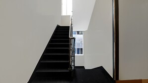 A staircase with black steps and a metal handrail, leading to a window with a view of the outside. - Treebo Blueberry Inn (Bengaluru)