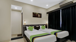 A hotel room with two beds, a painting on the wall, and an air conditioning unit. - Treebo Blueberry Inn (Bengaluru)