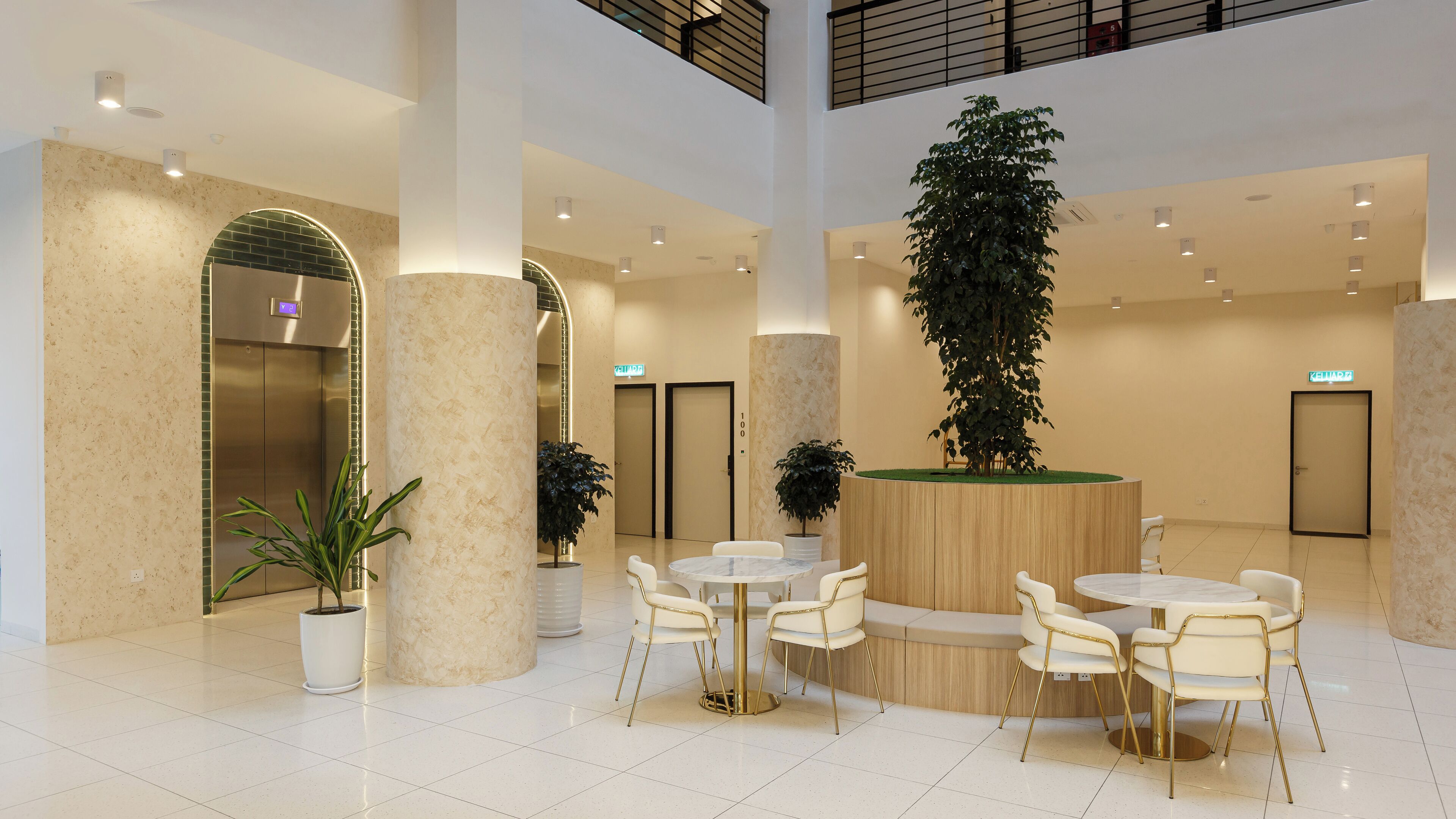 A modern lobby with a central seating area, a large potted plant, and an elevator.