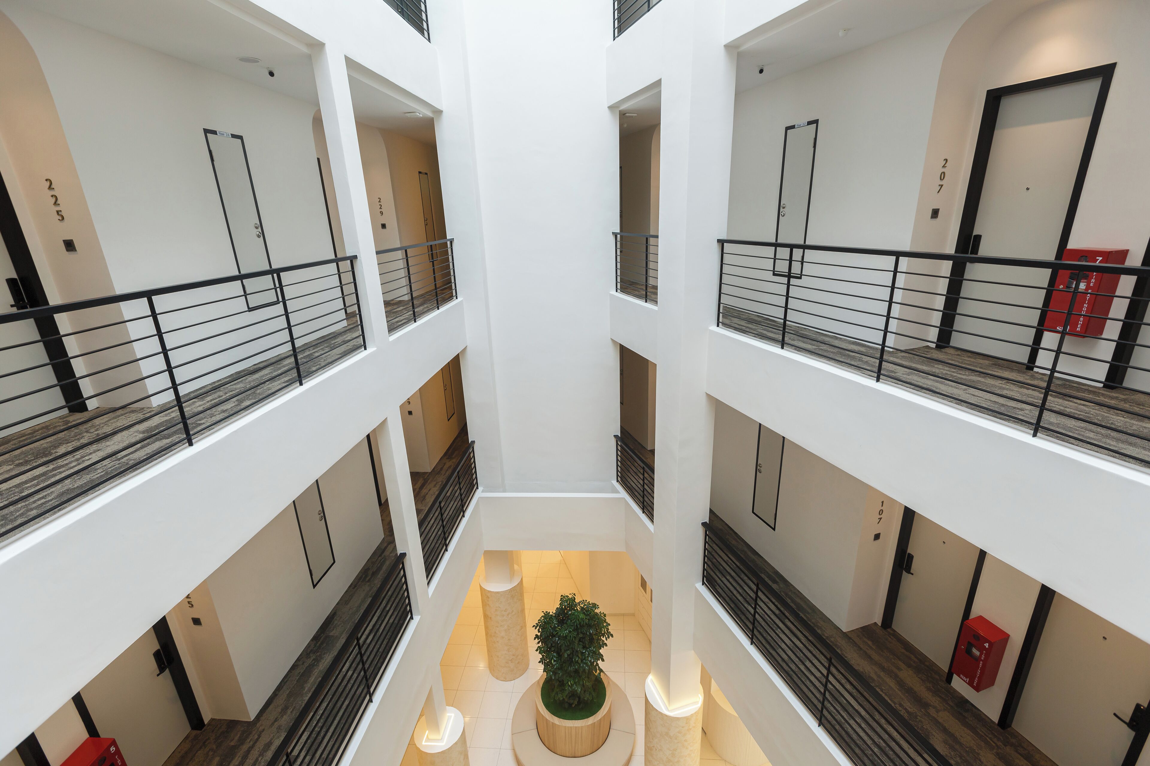 Interior de varios niveles con un atrio central, varios balcones y una planta en el centro.