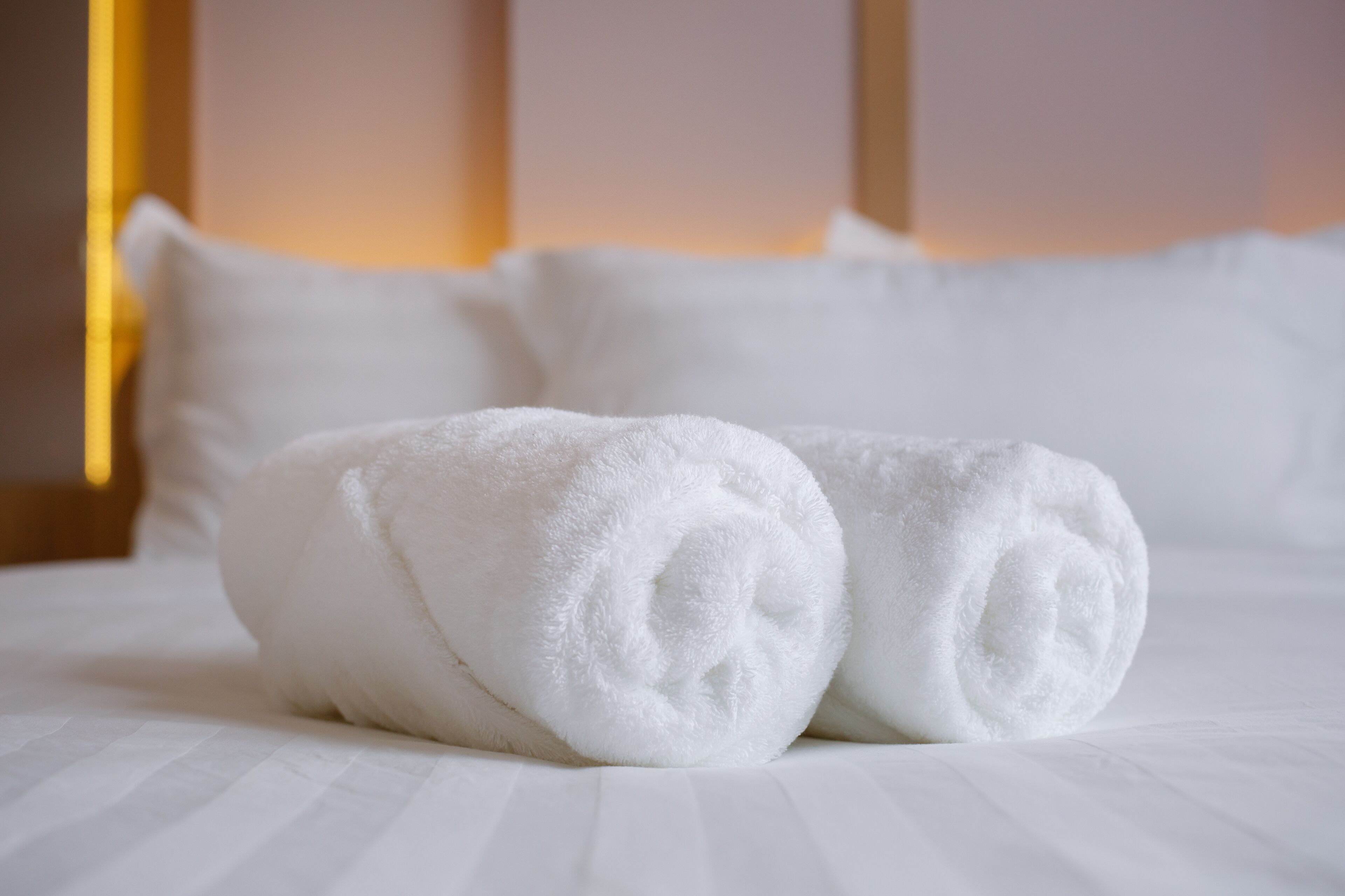A neatly made bed with white linens and pillows.