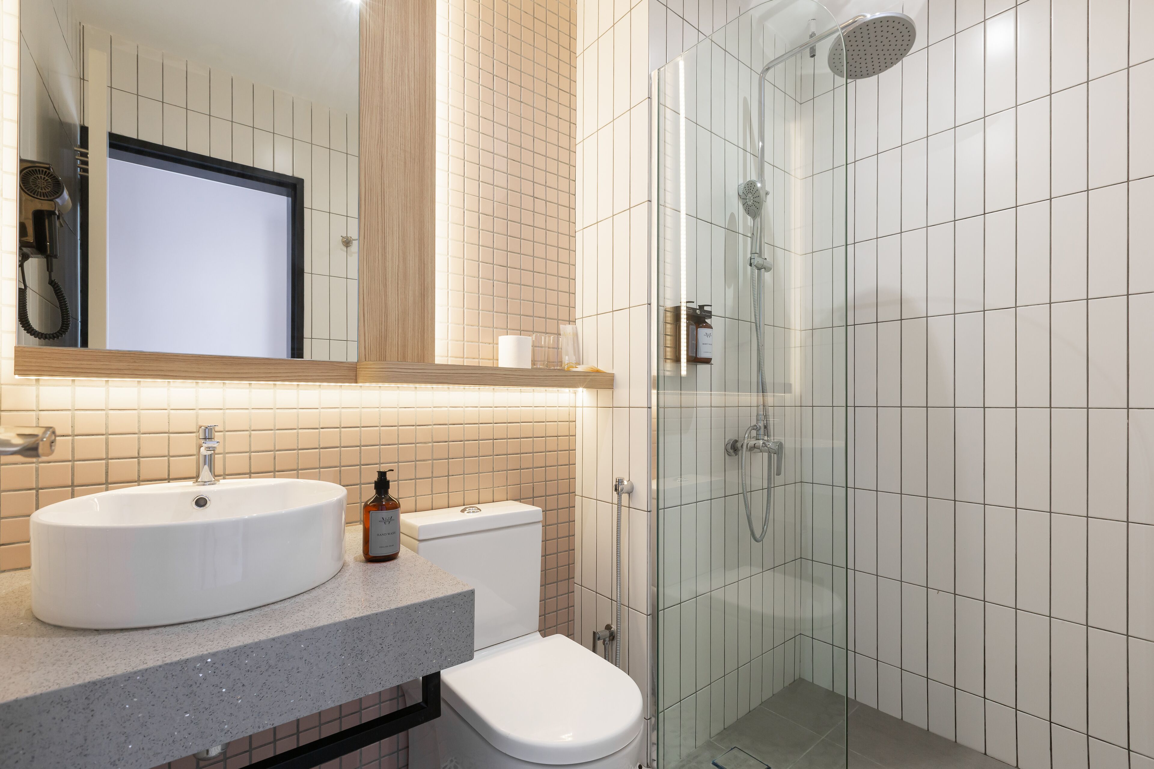 Un baño moderno con lavamanos, inodoro y ducha con mampara de vidrio.