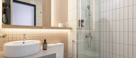 Un baño moderno con lavamanos, inodoro y ducha con mampara de vidrio.