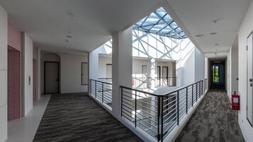A spacious corridor with a high ceiling, a glass skylight, and a fire extinguisher on the right.